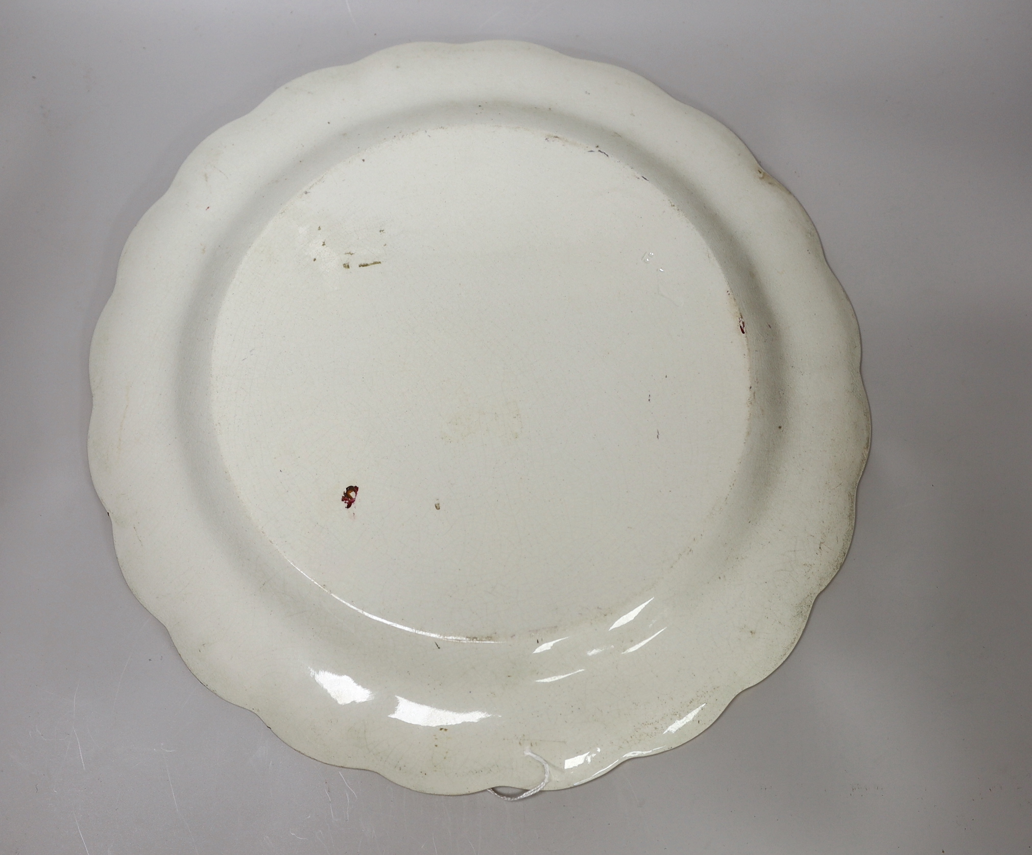 A mid 19th century English pottery charger painted with a coastal landscape under a light green border signed W. Thomas, indistinct factory and registration mark 39cm in diameter